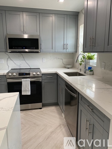 A kitchen with a white countertop and grey cabinets.