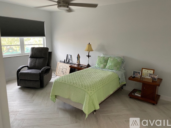 A bedroom with a bed, chair, and table.
