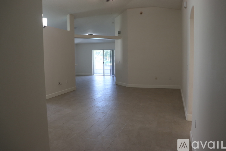 A spacious room with tiled flooring and a doorway leading to another room.