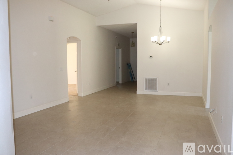 A spacious room with a chandelier and a doorway leading to another room.