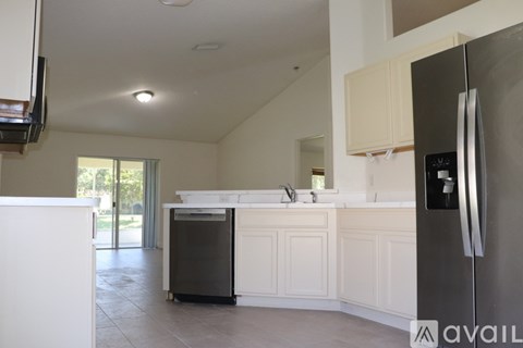 A kitchen with white cabinets and a black fridge.