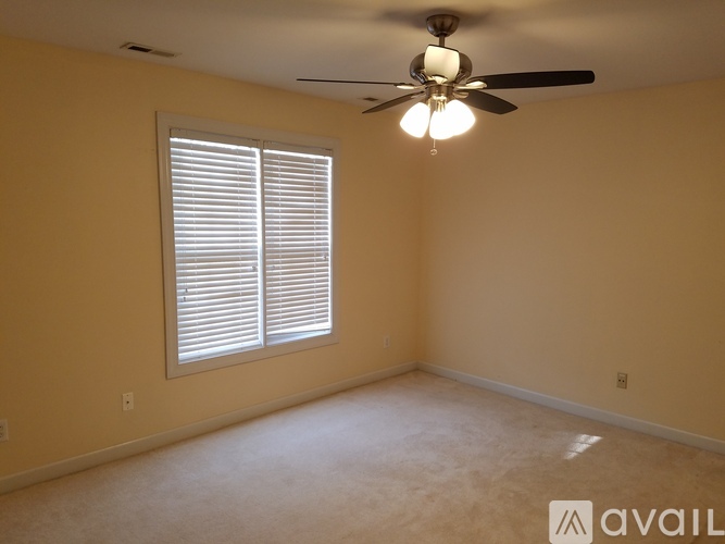 A room with a ceiling fan and a window with blinds.