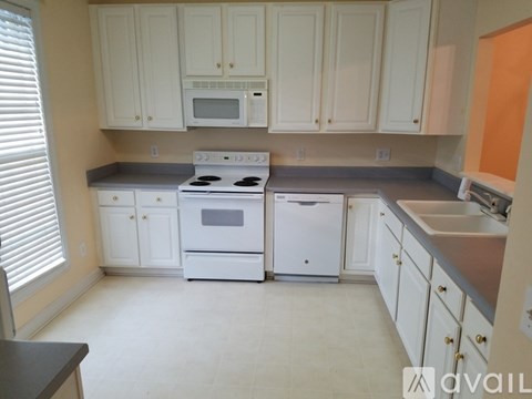 A kitchen with white appliances and cabinets.