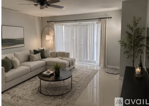 A living room with a white sofa, a black coffee table, and a ceiling fan.