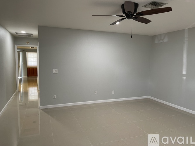 A spacious room with a ceiling fan and a doorway leading to another room.