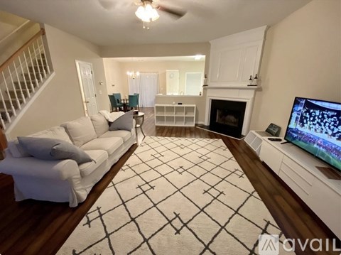 A living room with a white couch and a television on a white stand.