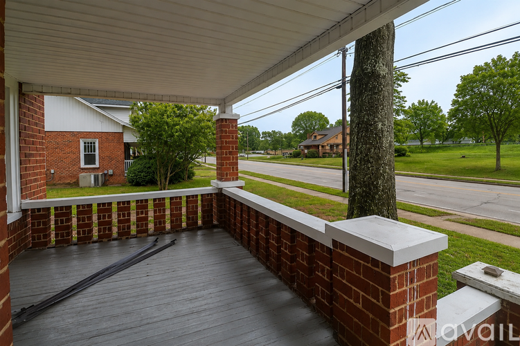 A porch with a brick wall and a wooden floor.