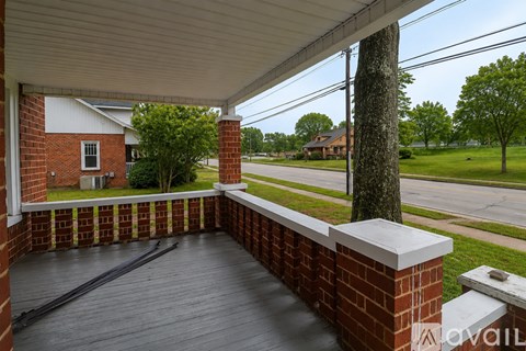 A porch with a brick wall and a wooden floor.
