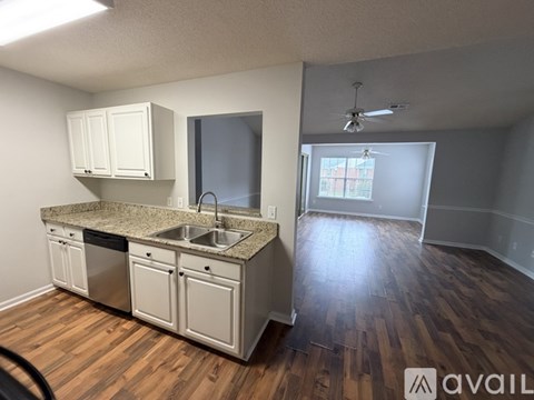 A kitchen with white cabinets and a wooden floor.