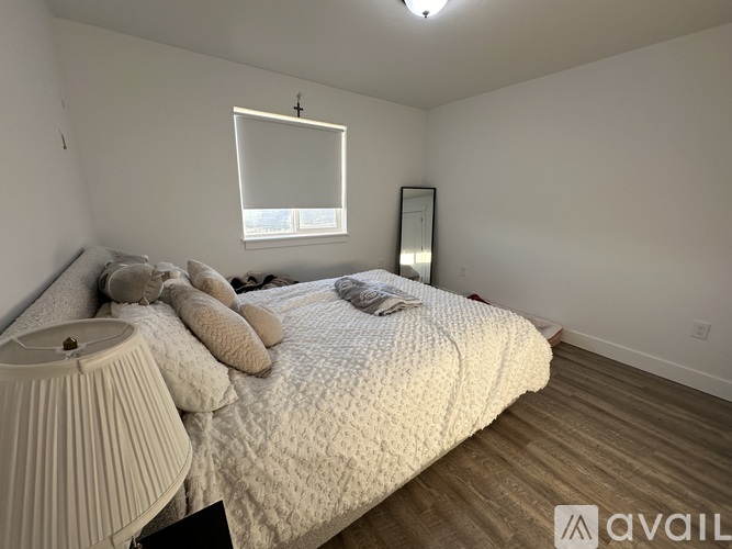A bedroom with a large bed and a window with blinds.