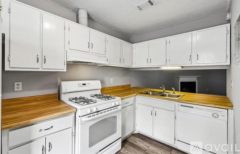 A kitchen with white cabinets and a wooden countertop.