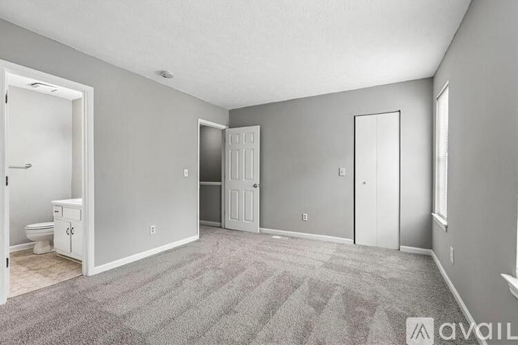 A spacious room with a carpeted floor and a toilet visible through the door.