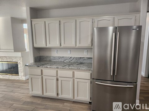 A kitchen with a stainless steel refrigerator and white cabinets.