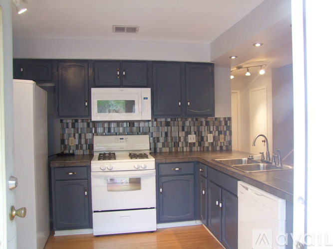 A kitchen with a white stove and black cabinets.