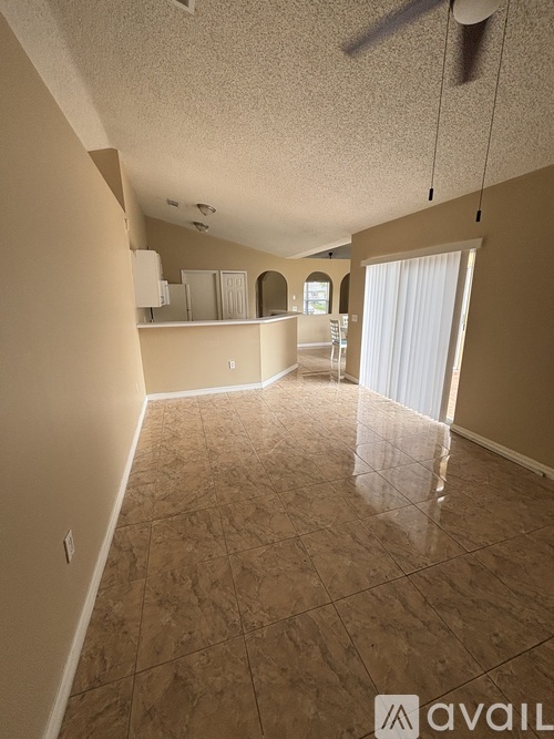 A spacious room with beige walls and floor tiles.