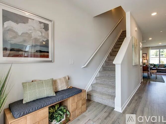 A living room with a staircase and a painting on the wall.