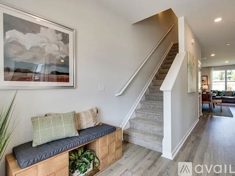 A living room with a staircase and a painting on the wall.