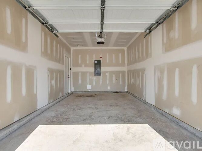 A spacious garage with a concrete floor and walls covered in drywall.