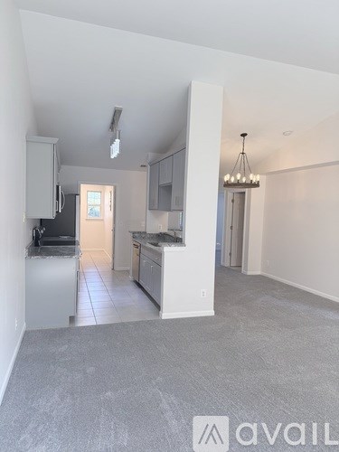 A spacious kitchen with white cabinets and a grey floor.