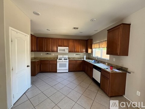 A kitchen with white appliances and brown cabinets.