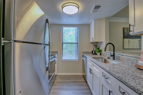 A kitchen with a refrigerator, sink, and cabinets.