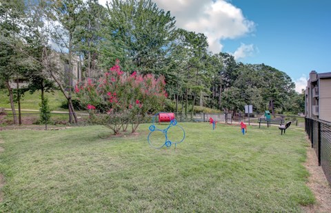 A park with a playground and a fence.
