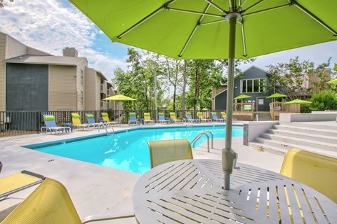 A pool with a table and chairs and an umbrella.