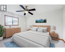 A bedroom with a large bed, a ceiling fan, and a painting of a mountain landscape on the wall.
