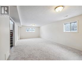 A spacious room with a carpeted floor and a window with blinds.