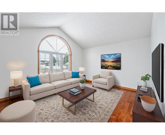 A living room with a large window, a sofa, a chair, a coffee table, and a painting on the wall.