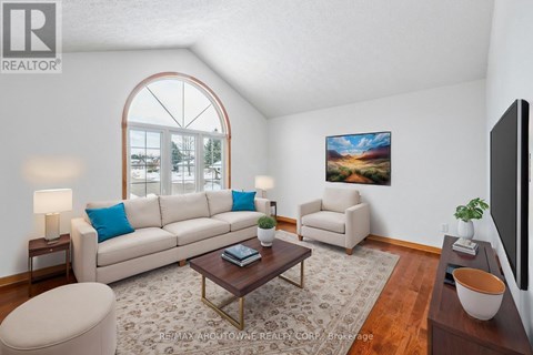 A living room with a large window, a sofa, a chair, a coffee table, and a painting on the wall.