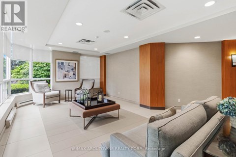 A spacious living room with a grey sofa, a coffee table, and a painting on the wall.