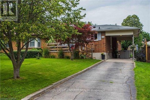 A house with a driveway and a tree in front of it.
