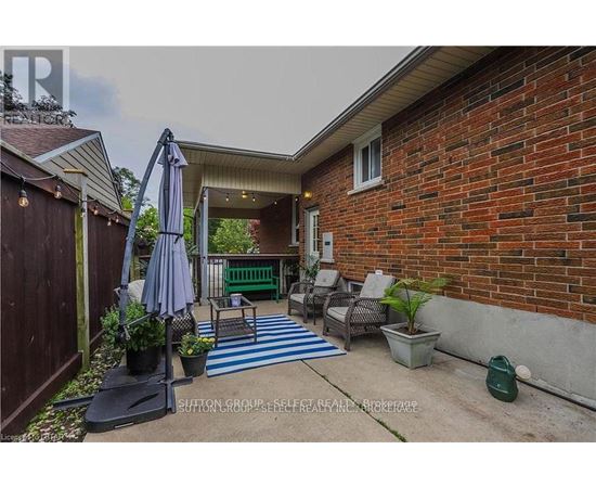 A patio with a blue and white striped rug, a table with chairs, and a potted plant.