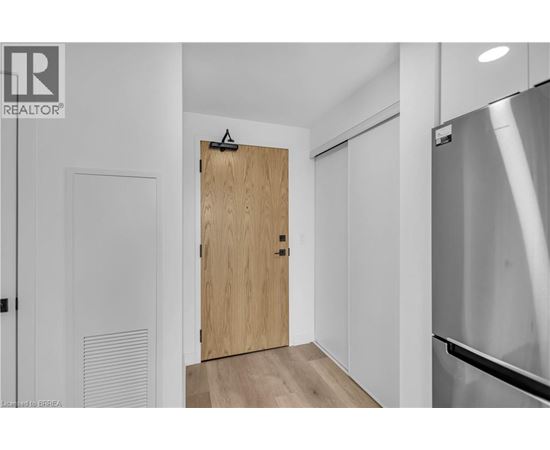 A modern kitchen with a wooden door and a stainless steel refrigerator.