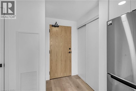 A modern kitchen with a wooden door and a stainless steel refrigerator.