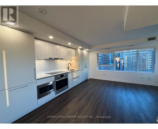 A kitchen with white cabinets and a window with blinds.