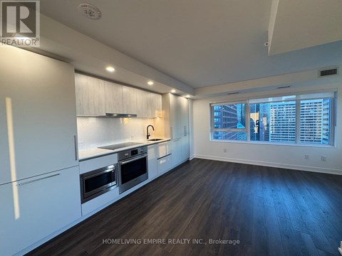 A kitchen with white cabinets and a window with blinds.