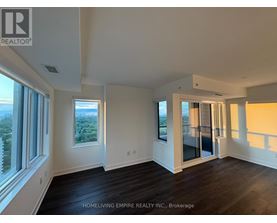 A spacious room with wooden floors and large windows overlooking a cityscape.