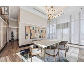 A dining room with a white table and chairs, a chandelier, and a large abstract painting on the wall.