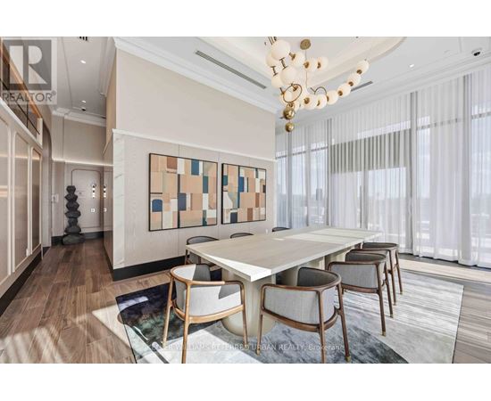 A dining room with a white table and chairs, a chandelier, and a large abstract painting on the wall.