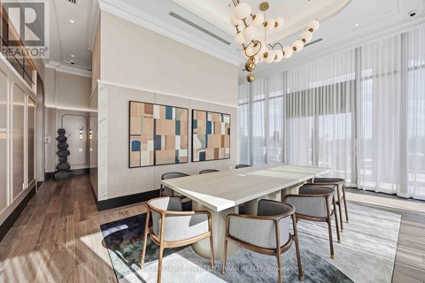A dining room with a white table and chairs, a chandelier, and a large abstract painting on the wall.