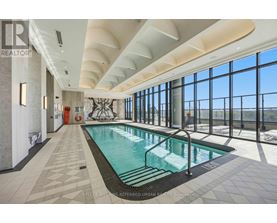 A large indoor swimming pool with a tiled floor and a glass wall overlooking the outdoors.