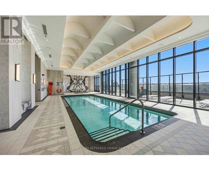 A large indoor swimming pool with a tiled floor and a glass wall overlooking the outdoors.