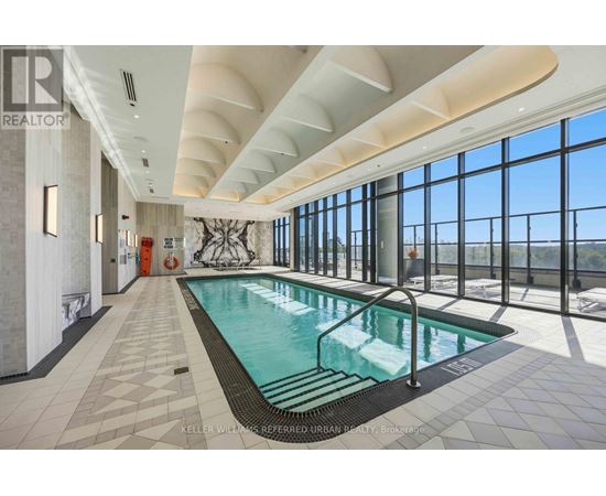 A large indoor swimming pool with a tiled floor and a glass wall overlooking the outdoors.