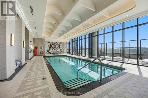 A large indoor swimming pool with a tiled floor and a glass wall overlooking the outdoors.