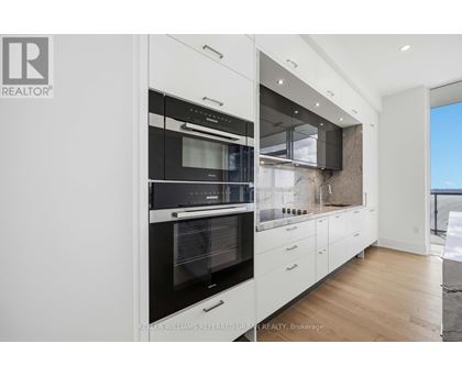 A modern kitchen with white cabinets and a black oven.