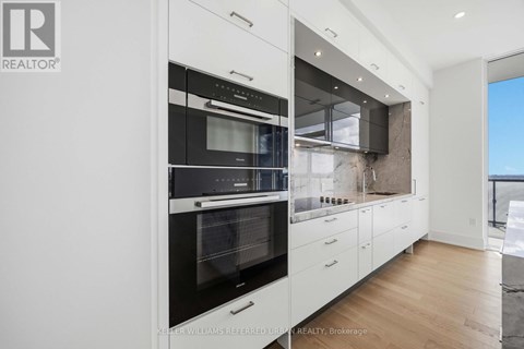 A modern kitchen with white cabinets and a black oven.
