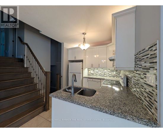 A kitchen with granite countertops and a staircase.