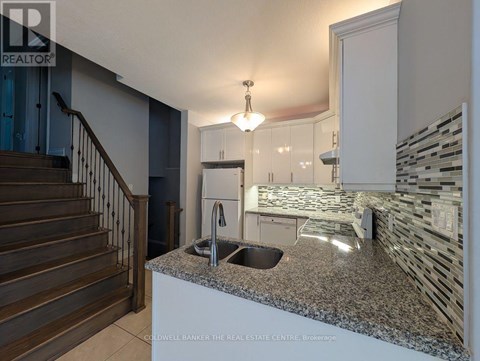 A kitchen with granite countertops and a staircase.